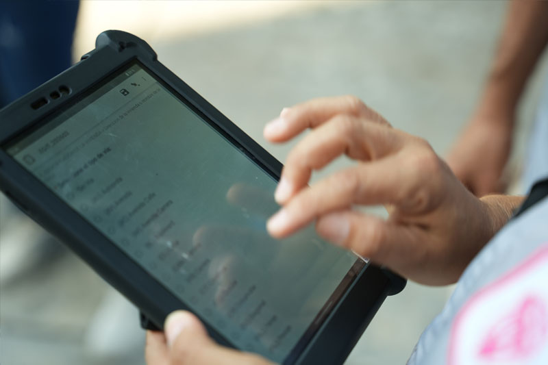 Primer plano de las manos de un censista ingresando información en un formulario de una tableta digital.