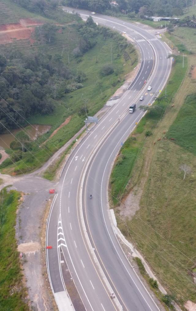 Vista aérea de autopista de doble calzada que serpentea entre colinas verdes con vegetación.